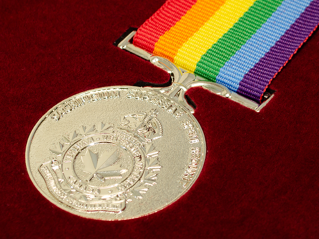 Custom military medal with a rainbow ribbon in a red box.